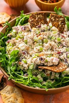 a bowl filled with salad next to crackers