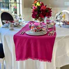 the table is set with pink flowers and silverware