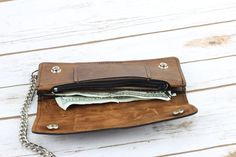 a wallet with money sticking out of it on top of a white wooden table next to a chain