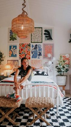 a woman sitting on top of a bed in a room with lots of pictures on the wall