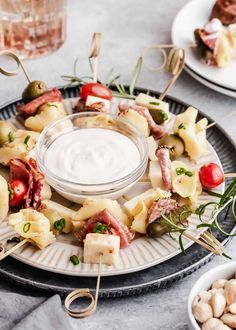 an assortment of appetizers on a plate with dip in the middle and other food items