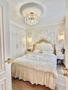 a white bed sitting in a bedroom next to a doorway with a chandelier above it