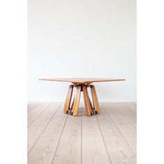 a wooden table sitting on top of a hard wood floor next to a white wall