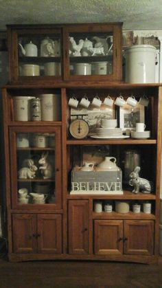 a wooden cabinet with glass doors and shelves filled with dishes