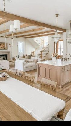 a large open concept living room and kitchen area with wood flooring, white couches, wooden dining table, and chandelier