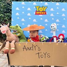 a young boy sitting in a toy story box with stuffed animals and toys behind him