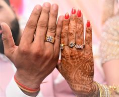 two people holding their hands up to each other with wedding rings on top of them