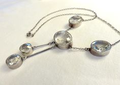 Originally $650.00. Circa 1930. Gorgeous Art Deco Era necklace featuring clear faceted crystal stones of oval and round shapes bezel set in Sterling Silver. This elegant necklace is a beautiful and versatile piece that could be worn for day or evening. It would be a wonderful piece to layer with other Deco crystal and paste pieces. Measurements: Central oval stone: Approx. 20mm x 15mm Oval stones on each side of the central Stone: Approx. 12mm x 8mm 2 round dangling round stones: Approx. 11mm in Vintage Formal Necklace With Single Cut Diamonds, Art Deco Silver Necklace With Single Cut Diamonds, Vintage Necklace With Single Cut Diamonds For Formal Occasions, Vintage Single Cut Diamond Necklace For Formal Occasions, Vintage Single Cut Diamond Necklaces For Formal Occasions, Formal Art Deco Necklaces With Single Cut Diamonds, Vintage Oval Necklace With Rose Cut Diamonds, Vintage Oval Necklaces With Rose Cut Diamonds, Vintage Silver Necklace With Single Cut Diamonds