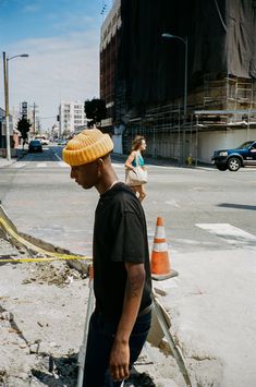 a man standing on the side of a road with a skateboard in his hand