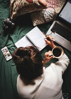 a woman sitting on top of a bed with a cup of coffee in front of her