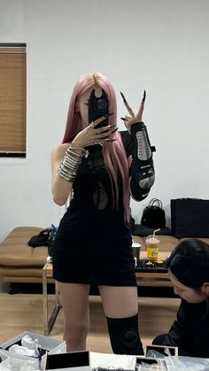 a woman with pink hair is taking a selfie in front of a man holding a camera