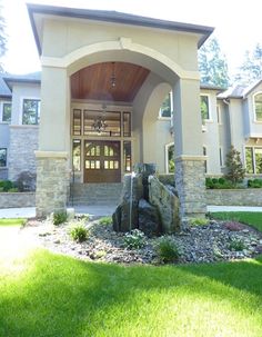 the front entrance to a house with rocks and grass