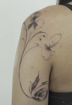 the back of a woman's shoulder with flowers and butterflies on it