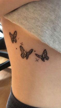 two butterflies on the side of a woman's right ribcage, which is black and white