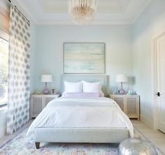 a large white bed sitting in a bedroom under a chandelier