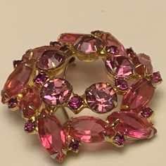 "This beautiful brooch features gorgeous pink rhinestones in various shades and has a simple, yet enchanting, silhouette. The colors range from a pale rosy blush to ruby pink to a deep magenta. The larger stones have open backs and many of the stones have \"fang like\" prongs, both typical of Juliana pieces. Approximately 1.5 inches in diameter and in very good vintage condition, though the pin could use some straightening." Vintage Pink Brooches For Evening, Antique Pink Brooch Jewelry, Unique Handmade Pink Brooches, Pink Flower Brooch Pins, Crystal Brooch Pink, Pink Wreath, Pink Rhinestones, Stone, Pink