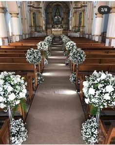 the aisle is lined with white flowers and greenery