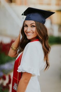 a woman wearing a graduation cap and gown posing for the camera with her hand on her head