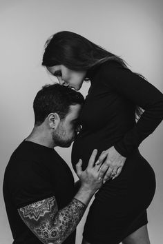 a man and woman standing next to each other with their hands on their stomachs