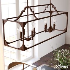 a chandelier hanging from the ceiling over a dining room table with flowers on it