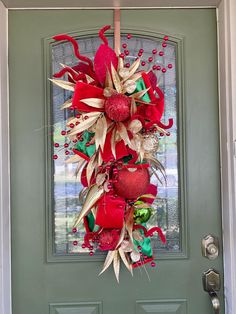 a christmas wreath hanging on the front door with poinsettis and bells attached to it