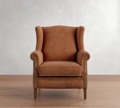 a brown chair sitting on top of a hard wood floor next to a white wall