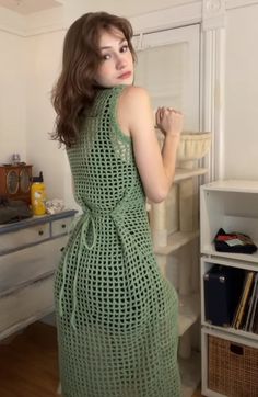 a woman in a green dress standing next to a book shelf