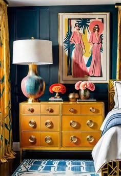 a bedroom with blue walls, gold dressers and paintings on the wall above it