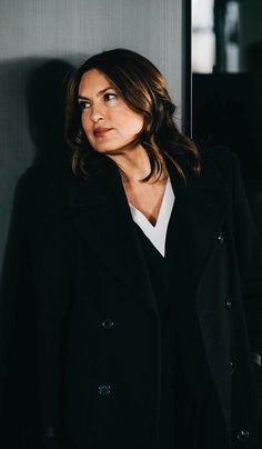 a woman wearing a black coat and white shirt