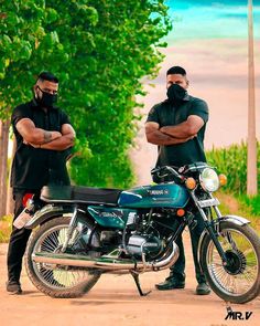 two men standing next to a motorcycle on a dirt road