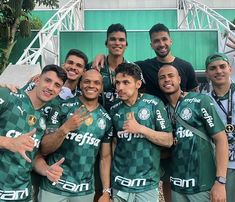 the soccer team is posing for a group photo in front of a green and white building