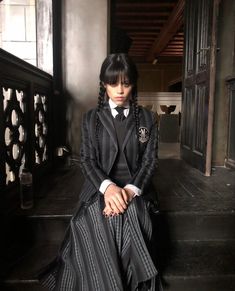 a woman sitting on steps wearing a black and white dress with long braids in her hair