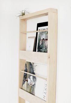 a wooden shelf with pictures and plants on it's sides, against a white wall