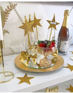 the table is decorated with gold stars and wine glasses, strawberries, champagne bottles, and candles