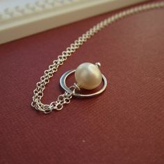 A petite freshwater pearl is encircled by a delicate sterling silver frame. Both dangle from sterling silver chain. Dainty freshwater pearl measures about 7mm; silver ring about 12mm. 18 inch necklace chain. All metal findings are *solid* sterling silver. Cultured freshwater pearl. >>To enter to my shop<< http://www.kgarnerdesigns.etsy.com Please contact me PRIOR TO PURCHASE if you are ordering on a deadline. I can usually accommodate quick shipping if I am made aware of your deadlin Dainty Sterling Silver Pearl Necklace With Round Pendant, Silver Sterling Silver Pearl Necklace With Pearl Charm, Dainty Sterling Silver Pearl Necklace In Silver, Dainty Silver Sterling Silver Pearl Necklace, Sterling Silver Necklace With Pearl Charm, Minimalist Sterling Silver Pearl Necklace With Charm, Dainty Round Sterling Silver Pearl Necklace, Dainty Sterling Silver Round Pearl Necklace, Dainty Sterling Silver Pearl Necklace