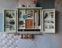 a wall mounted jewelry cabinet filled with lots of earrings