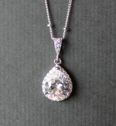 "Classic and elegant! Our 'Tamara' teardrop pendant is made with a sparkling multifaceted crystal pear and surrounded by a halo of matching Swarovski crystals set in a tarnish free rhodium base. We have used a matching 16.5\" rhodium plated fine cable chain, with a 2\" extender to complete this delicate necklace. PLEASE NOTE: This listing is for the necklace ONLY. 💙This item is also available in 18K Gold and 18K Rose Gold. ★★Items that are frequently bought together with the \"Tamara necklace\" Elegant Teardrop Halo Jewelry, Elegant Teardrop Halo Setting Jewelry, Elegant Pear-shaped Drop Necklace Gift, Pear Shaped Brilliant Cut Wedding Jewelry, Pear-shaped Bridal Necklace With Diamond Accents As Gift, Classic Pear-shaped Bridal Necklace, Classic Pear-shaped Bridal Necklace Gift, Formal Teardrop Halo Jewelry, Formal Teardrop Halo Setting Jewelry