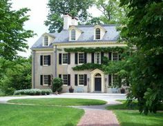 a large white house sitting on top of a lush green field