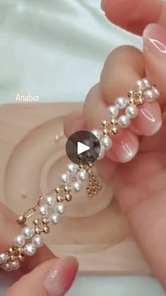 a woman holding onto a bracelet with pearls on it