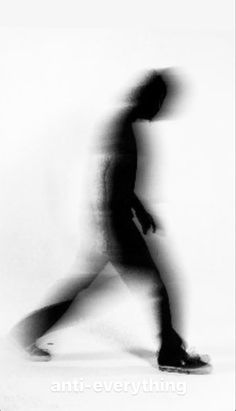 a blurry image of a man walking with his foot on the ground and head turned to the side