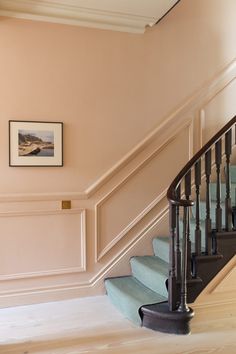 a stair case next to a painting on the wall in a room with pink walls