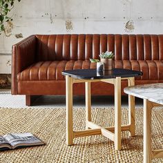 a brown leather couch sitting next to a table with a potted plant on it