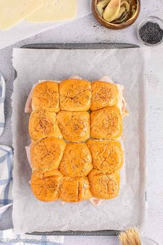 a tray filled with rolls on top of parchment paper next to butter and other ingredients