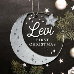 a personalized ornament hanging from a christmas tree with stars and the words leoi first christmas on it