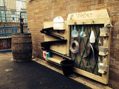 a wooden shelf with pots and pans hanging from it's sides next to a brick wall