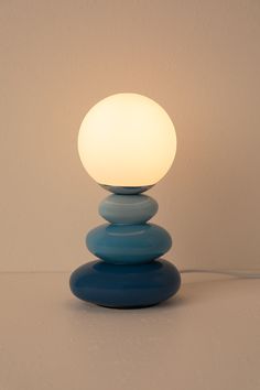 a blue lamp sitting on top of a white table next to a light bulb in the shape of a ball