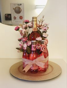 a bottle filled with lots of pink flowers on top of a table