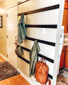 the coat rack is holding coats and purses on it's hooks, along with two handbags