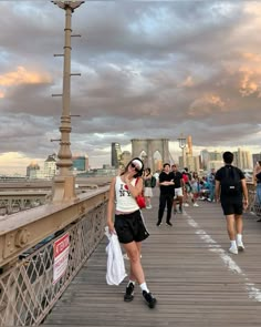 a woman is standing on a bridge and talking on her cell phone while others walk by