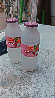 two plastic bottles with straws in them sitting on a table